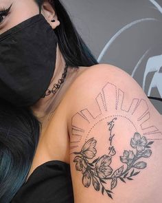 a woman wearing a face mask with flowers on her arm and behind her is a sun tattoo