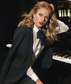 a woman posing in front of a piano with long hair and red lipstick on her lips