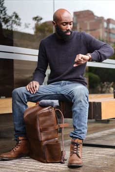 a man sitting on a bench next to a suitcase