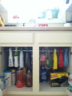 an open cabinet filled with cleaning products on top of a counter