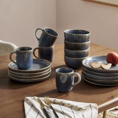 a wooden table topped with plates and cups