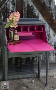 an old desk with pink drawers and flowers on it in front of a barn door