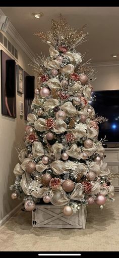 a decorated christmas tree in a living room with silver and pink ornaments on the top