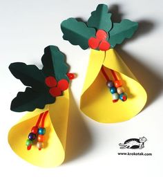 two paper bell shaped like christmas trees with beads on the top and one has green leaves