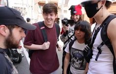 a group of people standing next to each other on a street with one person wearing a face mask