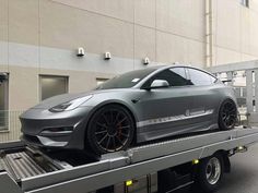 a silver car is on the back of a flatbed truck