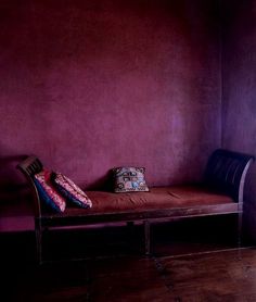 a wooden bench sitting in front of a purple wall