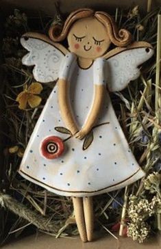 an angel figurine in a box with flowers and grass around it's edges