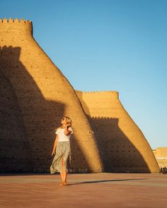 a woman is walking in front of a wall