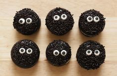 six chocolate donuts decorated with black sprinkles and fake googly eyes