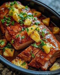 meat with pineapple sauce and parsley on top in a black bowl, ready to be eaten