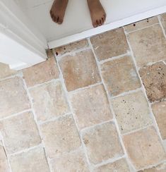 a person's bare feet are standing on the edge of a tile floor next to a door