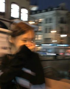 a blurry photo of a woman talking on her cell phone in the city at night