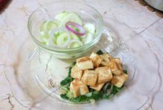 a glass bowl filled with cucumbers next to another bowl full of diced vegetables