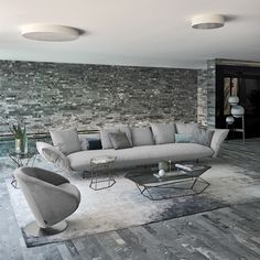 a living room filled with furniture next to a stone wall covered in grey tiles and pillows