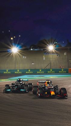 two racing cars driving on a track at night