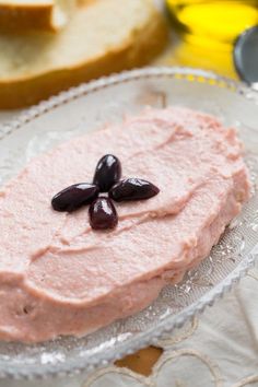 a piece of bread with olives on it sitting on top of a glass plate