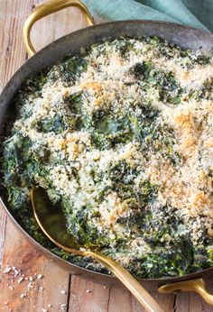 a skillet filled with spinach and cheese on top of a wooden table