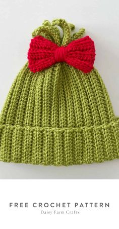 a green knitted hat with a red bow on top and the words free crochet pattern below it