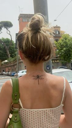 a woman with a dragonfly tattoo on her upper back neck and behind her is a green purse