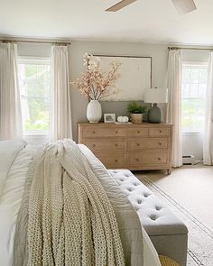 a bedroom with a bed, dresser and ceiling fan