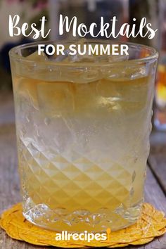 a glass filled with ice sitting on top of a wooden table next to a yellow coaster