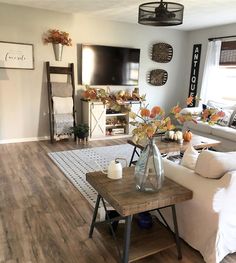 the living room is clean and ready to be used for fall decor purposes are white couches, wood coffee table with vases on it