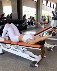 a woman laying on top of a bench in a gym