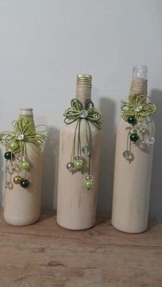 three wine bottles decorated with bows and beads