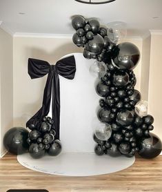 black and silver balloons are on display in the corner of a room with a chandelier