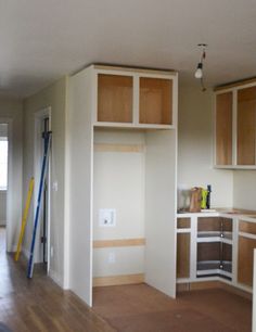 an empty kitchen with wooden cabinets and hard wood flooring in the middle of it