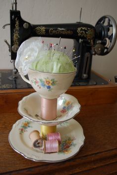 three plates stacked on top of each other in front of a sewing machine and thread spools