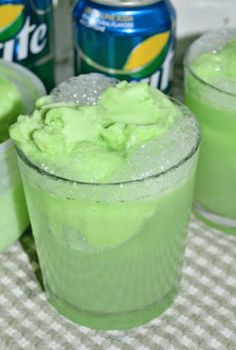 two glasses filled with green liquid next to cans of diet coke and an empty can