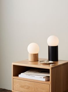 two lights are sitting on top of a wooden table