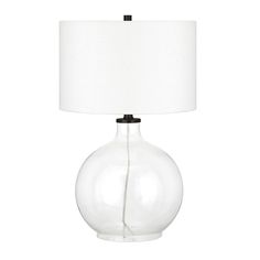 a clear glass table lamp with a white shade on the bottom and a black base