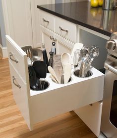 an open drawer in the middle of a kitchen with utensils and spoons