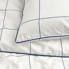 two pillows on top of each other in front of a white and blue checkered comforter