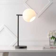 a white table with a lamp and some flowers on it