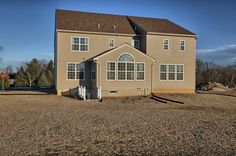 a large two story house sitting in the middle of a field with lots of dirt