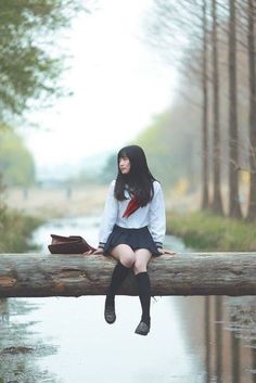 a woman sitting on a log in the rain