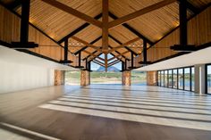 an empty room with large windows and wooden beams on the ceiling is seen in this image