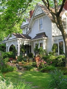 a large white house surrounded by trees and flowers