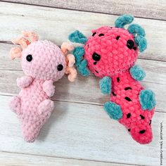 two crocheted stuffed animals sitting next to each other on top of a wooden table