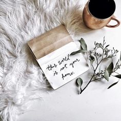 a cup of coffee next to a paper bag with writing on it and some leaves