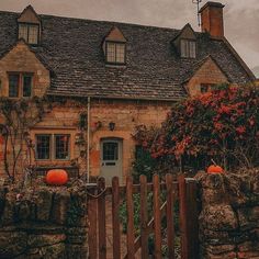 an old house with pumpkins on the fence