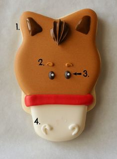 a cookie shaped like a cat with ears and tail on it's head, has numbers in front of it