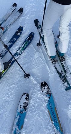 two skiers are standing in the snow with their skis on and feet propped up