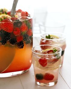 three glasses filled with different types of fruit and ice on top of a white table