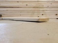 a piece of wood sitting on top of a white floor next to a pile of wooden planks