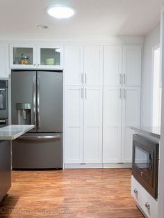 a modern kitchen with stainless steel appliances and white cabinetry, including an oven in the center